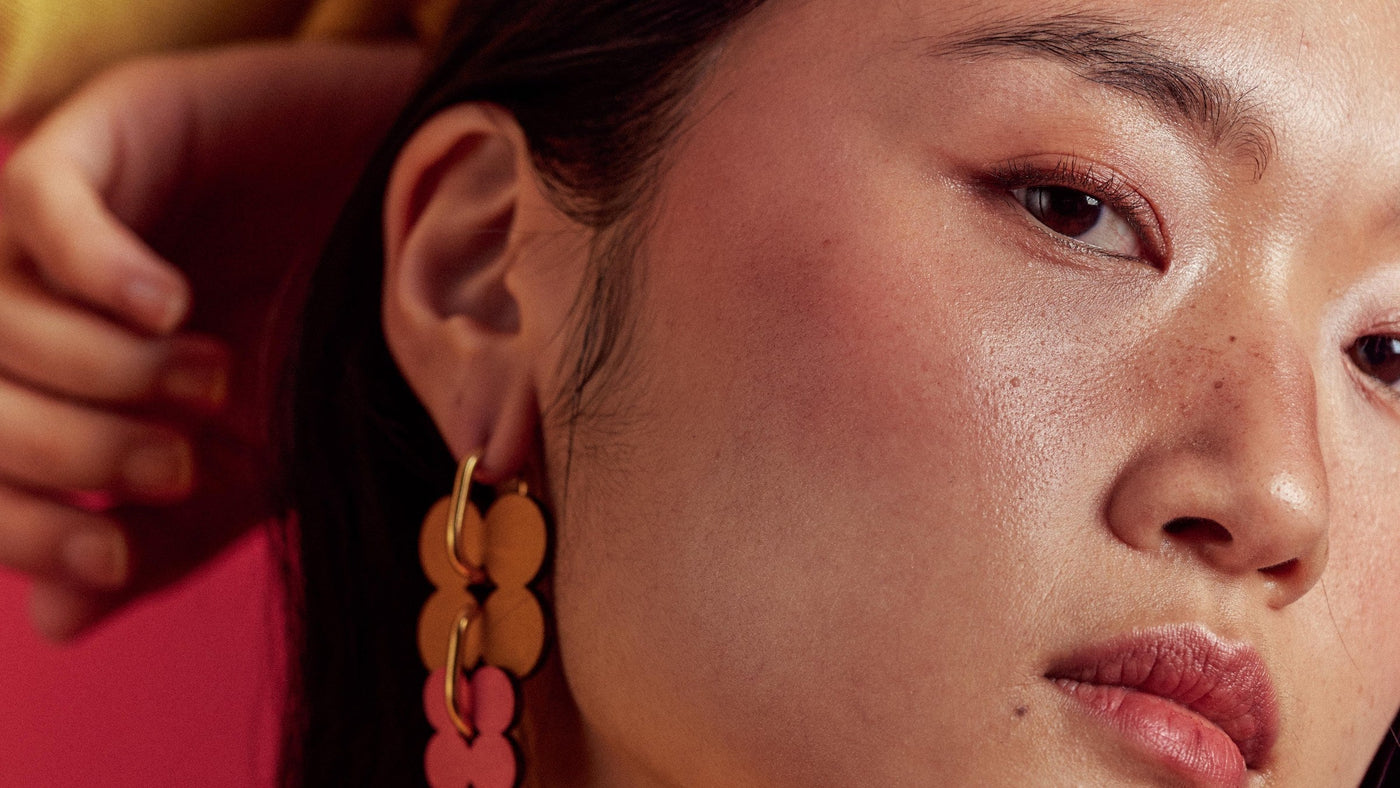 ISLI Studio statement earrings photographed on a coloured backdrop