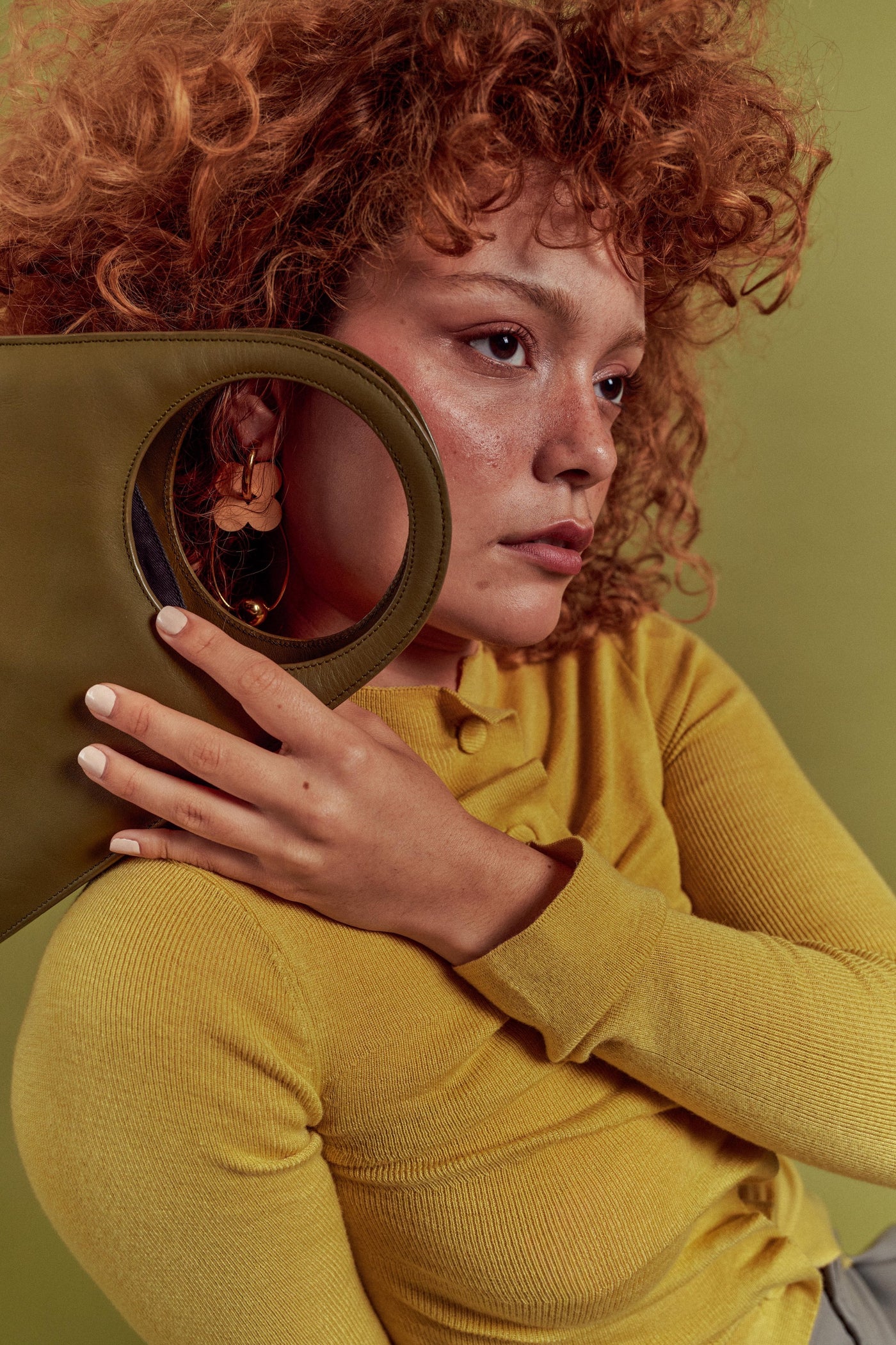 A model holding an olive leather ISLI Studio bag with a circular cut-out handle