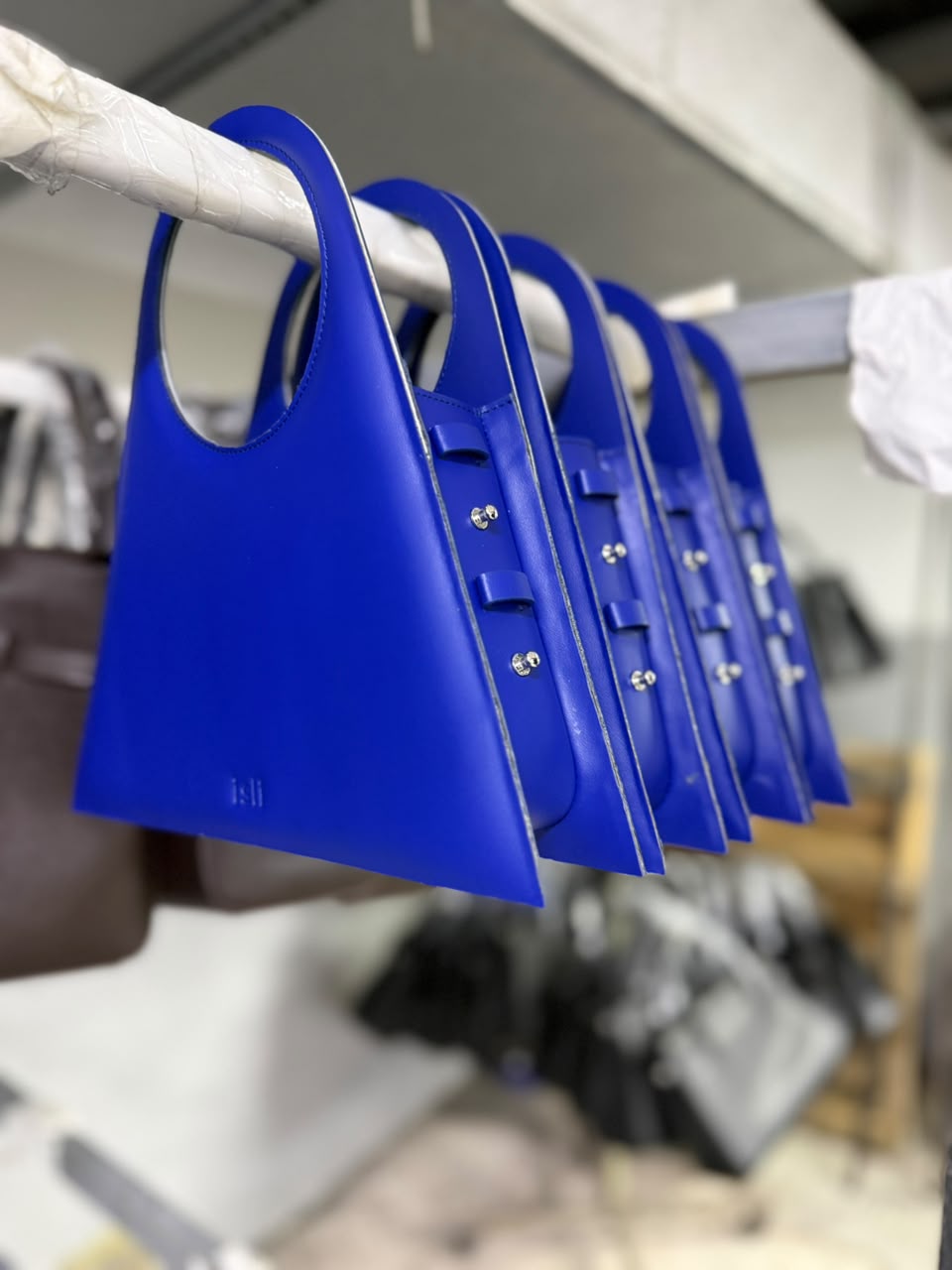 Electric blue Toubkal bags hanging in a row, finished and ready to leave the workshop.
